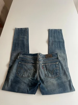 Levi's blå straight fit jeans - Säljer ett par klassiska blå Levi's jeans med straight fit. Jeansen har fem fickor, dragkedja och knapp framtill samt ikonisk Levi's-lapp på bakfickan. Perfekt för dig som gillar tidlös denimstil.