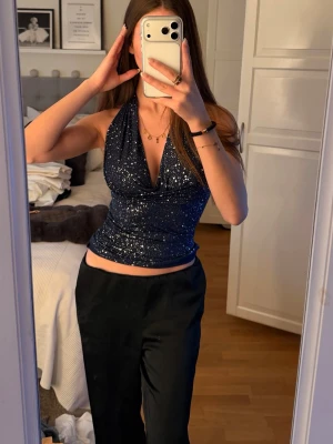 Glittrig mörkblå halterneck topp - Säljer en glittrig mörkblå halterneck topp med djup urringning och öppen rygg. Älskar den men får aldrig andvändning för den :/
