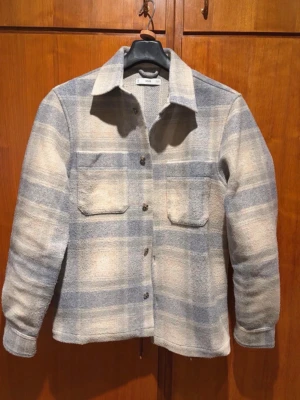 Blåvit rutig overshirt med fickor - Overshirt från Mango, köpt för 850kr:) Använd max 3 gånger. Inga tecken på användning. Perfekt nu till våren:)