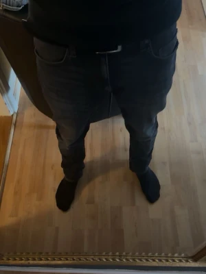 Tiger of sweden jeans - Säljer ett par svarta slim fit jeans med klassisk femficksdesign och normal midja. Jeansen har en stilren look och passar perfekt till en avslappnad streetstil. Materialet är troligtvis bomull med stretch för extra komfort.