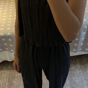  Blå glittrig jumpsuit - Säljer en snygg blå jumpsuit från Lindex med glittriga detaljer och volang vid axlarna. Materialet är syntet med ribbad struktur och små guldprickar som ger en festlig känsla. Byxdressen har ett loose passform och elastisk midja för extra komfort. Inte använd mycket så inga defekter. Den är i stl 146/152, men kanske passar någon som är 165 eller kortare då jag är 170, hör gärna av er om frågor!❤️(Säljer även på Vinted ifall man skulle vilja köpa där)