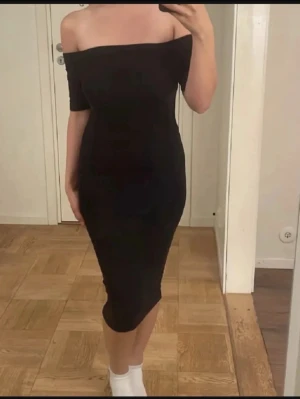 Svart offshoulder klänning - Säljer en svart, figurnära offshoulder klänning med midilängd. Klänningen har en stilren och enkel design utan synliga detaljer och passar perfekt för dig som gillar en klassisk look.