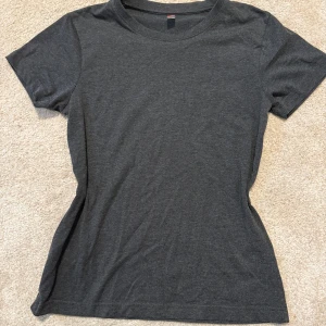 Mörkgrå t-shirt från Clique - En enkel och stilren mörkgrå t-shirt från Clique i klassisk modell. T-shirten har rund halsringning och korta ärmar. Tillverkad i mjuk bomull som känns skön mot huden. Perfekt basplagg till garderoben.