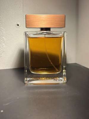 Dolce & Gabbana The One EdT 100ml - En lyxig herrparfym från Dolce & Gabbana, The One Eau de Toilette. Flaskan är i genomskinligt glas med en elegant, kopparfärgad fyrkantig kork. Innehållet är bärnstensfärgat och flaskan rymmer 100 ml. Nypris ligger runt 1000kr