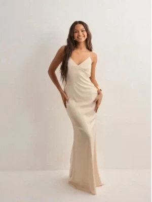 Champagnefärgad långklänning - Elegant långklänning i champagnefärg med öppen rygg. Klänningen har en v-ringad front och är figurnära med ett mjukt fall. Perfekt för dig som vill ha en stilren och lyxig look. Använd en gång och är insydd i midjan. Den är också slutsåld och går inte att köpa längre.