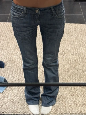 Blå bootcut jeans med detaljer - Blå/gråa bootcut jeans med snygga  detaljer. Jeansen har låg midja och är bootcut. Super fint skick. Skriv vid frågor eller mått💕