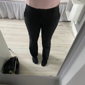 Bikbok Vera kostymbyxor - Säljer ett par klassiska svarta kostymbyxor med rak passform och hög midja. Byxorna har diskreta fickor bak och fram, samt hällor för skärp. Perfekta för en stilren look och passar till många olika outfits.