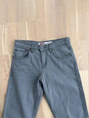 Gr ablekta Levi's jeans raka ben - Snygga grå jeans från Levi's med klassisk femficksmodell och raka ben. Jeansen har normal midja och är tillverkade i ett mjukt denimtyg. Perfekta för en avslappnad och trendig look.