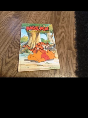 Nalle Puh Tigger blir uppskattad - En färgglad barnbok med hårda pärmar, 'Nalle Puh Tigger blir uppskattad', från Richters. Omslaget visar Nalle Puh och Tiger i en tecknad stil, typisk för Disney. Perfekt för dig som gillar klassiska sagor och äventyr i Sjumilaskogen.