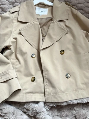Kort beige trenchcoat från RYVLS - Stilren kort trenchcoat i beige från RYVLS, endast använd få tal gånger , ny skick, pris går diskuteras 