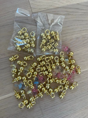 Guldfärgade berlocker och hängen/ bordsdekorationer  - Ett större parti guldfärgade berlocker och hängen i metall, blandat med några plastdetaljer i rosa och blått. Perfekta till DIY-smycken som armband, halsband eller örhängen. Alla delar har ögla för enkel montering.