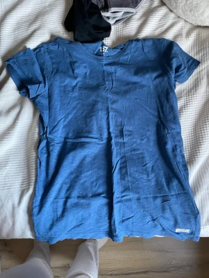 Blå t-shirt från 157 - En enkel blå t-shirt från 157 med rund hals och korta ärmar. Tillverkad i mjuk bomull, perfekt för en avslappnad stil. Klassisk passform utan tryck eller mönster.