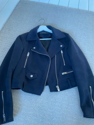 Svart skinnjacka från Zara Basic - Säljer min jätte fina mörkblå bikerjacka från Zara i mocka, storlek S. köptes på en second hand för 300 kr i Tyskland men säljer den enbart för 100 kr. Jackan är oanvänd och därav har inga defekter.