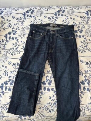 Mörkblå raka jeans från Levi's - Säljer ett par klassiska mörkblå jeans från Levi's med rak passform och fem fickor. Jeansen har kontrastsömmar och en liten logotyp på bakfickan. Tillverkade i slitstark denim som passar perfekt till en avslappnad stil.