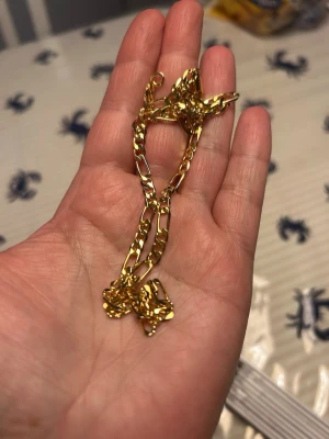 Muli collection kedjehalsband - Snyggt halsband i Guldplaterad med breda, platta länkar i klassisk kedjedesign. Halsbandet har en enkel och stilren look som passar till många olika outfits. Materialet ser ut som metall med en blank finish. Perfekt för dig som gillar trendiga accessoarer.