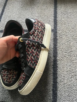 Zadig skor - Snygga sneakers med svart, rött och beige mönster på textil, svarta mockadetaljer och vita sulor. Skorna har svarta skosnören med gulddetaljer och en klassisk låg profil. Storleken är 38 men passar 39 också!!❤️