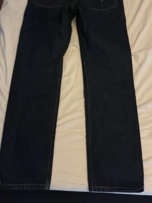 Mörkblå raka jeans från Levi’s - Snygga mörkblå jeans med rak passform och klassiska kontrastsömmar. Jeansen har fem fickor och är tillverkade i ett robust denimtyg. Perfekta för dig som gillar en tidlös och enkel stil.