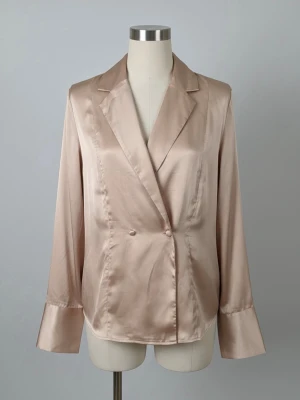 Champagnefärgad/ rosa satinblus  - Säljer en champagnefärgad satinblus från Gina Tricot med avslappnad passform och breda manschetter. Blusen har djup v-ringning, krage och långa ärmar. Perfekt att styla med jeans eller kjol för en trendig look.