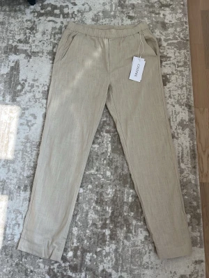Beige linnebyxor från Ciszere - Snygga beige linnebyxor från Ciszere med raka ben och resår i midjan. Nypris 1000:- i butik, senast kollat igår. Byxorna har två sidofickor och är tillverkade i ett luftigt linnematerial som passar perfekt för en avslappnad och trendig stil. 