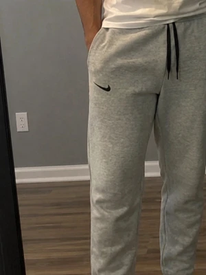 Gråa Nike sweatpants - Gråa shorts från Nike med svart broderad logga på vänster ben. Shortsen har svarta snören i midjan och sidofickor. Tillverkade i mjukt material som känns skönt mot huden, perfekt för träning eller chill.