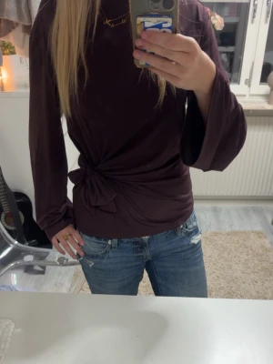 Mörklila/brun topp med knyt i sidan - !PRIS GÅR ATT DISKUTERA!!💗 Snygg mörklila långärmad topp med trendigt knyt i sidan. Toppen har en rak passform och vida ärmar som ger en avslappnad vibe. Perfekt att styla med jeans eller kjol för en cool look.
