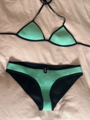 Triangl Bikini - Turkos bikini från Triangl Underdelen och överdelen är i st medium På undersidan finns små ”fläckar”, kanske går att tvätta men jag har inte testat. Köpt på vinted men passade inte så jag säljer vidare. Skriv om ni har några frågor!