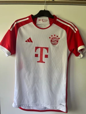 Bayern München matchtröja Müller 25 - Köpt på plats i München matchen mot Köln. Snygg vit och röd Bayern München matchtröja från Adidas med tryck av nummer 25 och Müller på ryggen. Tröjan har klubbmärke och Adidas-logga på bröstet samt Telekoms sponsortryck. Tillverkad i lätt och ventilerande material med Aeroready-teknologi.