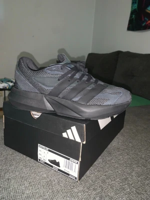 Adidas svarta sneakers med mesh och mocka - Snygga sneakers från Adidas i mörkgrått med svarta detaljer. Skorna har en chunky sula, ovandel i mesh och mocka samt klassiska tre ränder på sidan. Perfekta för dig som gillar sportig och modern stil.