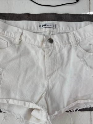 Vita jeansshorts med slitningar - Vita jeansshorts med slitningar, stlk L, knappt använda, dock en gulaktig fläck på bakfickan, kanske går att ta bort. 