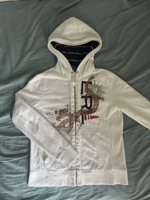 Vit Ralph Lauren hoodie - Säljer en eftertraktad hoodie från Ralph Lauren Jeans Company. Klassisk vit zip-up modell med ikoniska broderade detaljer, stort frontmotiv och exklusiva kontrastdetaljer i huvan. Ett perfekt plagg för dig som gillar vintage, Y2K och preppy/old money-estetik.                                                         📦 Snabb frakt 💬 Hör av dig vid frågor eller om du vill ha fler bilder.