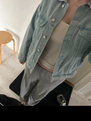 Ljusblå jeansjacka i klassisk modell - Snygg ljusblå jeansjacka med klassisk passform och silverfärgade knappar. Två bröstfickor med lock och knapp, samt raka sömmar för en tidlös look. Perfekt att slänga över en t-shirt för en avslappnad stil.