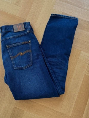 Nudie Jeans Steady Eddie  - Säljer ett par klassiska Steady Eddie från Nudie Jeans i en snygg mellanmörk blå tvätt. Modellen har en regular fit med en mer autentisk, rak siluett över benen och normalhög midja. Kan passa W32. Nyskick!!  W33 L32  Vid frågor eller funderingar hör av er! 