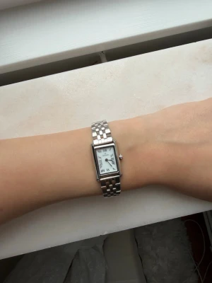 Mockbergs klocka i silver  - Superfin klocka i modellen timeless watch från Mockberg i storleken regular. Jag har varit och professionellt gjort länk armbandet mindre genom att ha tagit bort två länkar. Säljer då jag inte längre använder silversmycken. Kommer i original förpackning. Originalpris 1899kr! Priset kan diskuteras. 💕
