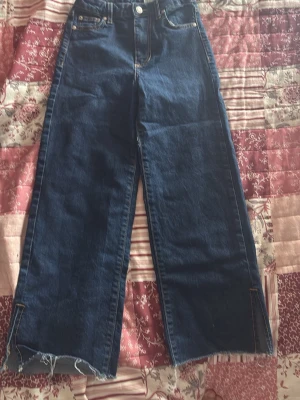 Mörkblå vida jeans med rå kant - Säljer ett par mörkblå jeans från Crocker med breda ben och råa, fransiga kanter nertill. Jeansen har hög midja, klassiska fem fickor och kontrastsömmar. Perfekta för en avslappnad och trendig look.