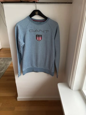 Ljusblå sweatshirt från GANT - Snygg Ljusblå GANT tröja i st 158-164 cm 13-14år för endast 175kr. Nypris 750kr.