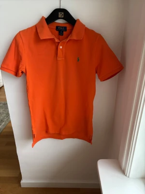 Orange pikétröja från Polo Ralph Lauren - Snygg Orange Ralph Lauren piké i st M 10-12 år för endast 125kr. Nypris 750kr 