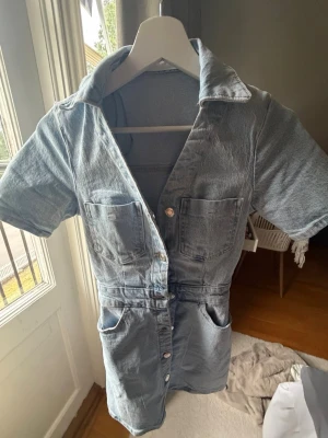 Ljusa denim klänning från Zara - Cool ljusblå denim klänning från Zara med korta ärmar, krage och knappar framtill. Två bröstfickor och två sidofickor.ifrån Zara och tror inte den säljs längre 💗endast använd en gång
