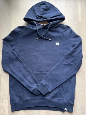 Les Deux hoodie - blå, L - Marinblå hoodie i storlek L från Les Deux. Högt nypris, men säljer då den blivit för liten. Tröjan är i bra skick, men det förekommer defekter i form av ett litet hål med lagning bakom huvan och detsamma vid framfickan (se bilder).