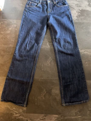 Mörkblå raka jeans från Zara - Säljer ett par mörkblå jeans från Zara med rak passform och klassisk femficksdesign. Jeansen har kontrastsömmar och en låg midja. Perfekta till en avslappnad stil och tillverkade i slitstark denim.