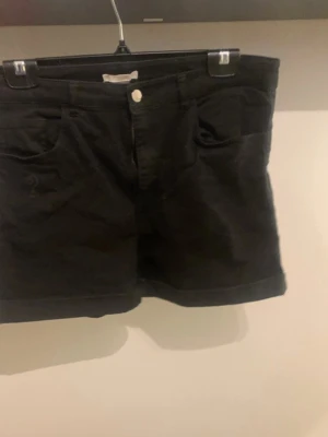 Svarta shorts  - Snygga svarta shorts med klassisk femficksmodell och uppvikta benslut. Stängs med knapp och dragkedja framtill. Perfekta till sommaren och passar till det mesta i garderoben. Stretchiga vid midjan!
