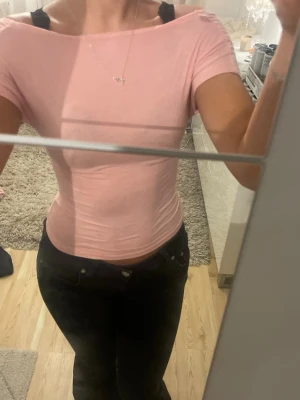 Ljusrosa topp med öppen rygg - Säljer en ljusrosa, tight topp med korta ärmar och snygg öppen rygg. Toppen har en croppad passform och är gjord i ett mjukt bomullsmaterial. Perfekt för dig som vill ha en enkel fin tröja 