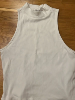 Vit ribbad linnetopp från Divided - Säljer en vit ribbad linnetopp från Divided by H&M. Toppen har hög hals och är ärmlös. Materialet är stretchigt, vilket gör den superbekväm. Ser snyggare ut på, använt några gånger men säljer då den inte passar längre. Det står M i storlek men är väldigt lite så skulle passa S.