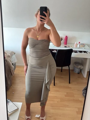 Sandfärgat set från zara kjol+body - Snygg sandfärgad/khaki axelbandslös body med draperad överdel och tillbehörqnde kjol med  dekorativ volangdetalj på sidan. Settet har en figurnära passform och är tillverkad i ett mjukt, stretchigt material som ger en elegant siluett. Aldrig hunnit användas. Nypris 650kr. 