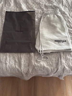 Grå Essentials shorts med snörning - Snygga ljusgrå shorts från Essentials med elastisk midja och långa snören framtill. Mjuk bomullskänsla och logga tryckt på ena benet. Perfekta för chill dagar eller när du vill ha en clean och enkel stil.
