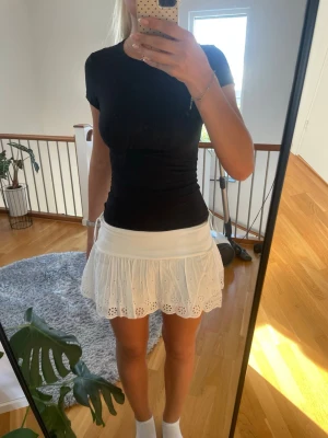Vit kort kjol med broderade detaljer - Söt vit kortkjol med broderade blommönster och vågig kant. Kjolen har en luftig och lätt känsla, perfekt för varma dagar. Den har en feminin och ungdomlig stil med fina detaljer i tyget. Kjolen är inprincip helt ny, bara testat den någon gång 