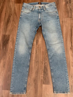 Ljusblå raka jeans från Lee - Säljer ett par ljusblå jeans från Lee med klassisk femficksmodell och raka ben. Jeansen har en snygg tvätt med subtila slitningar och Lee-lapp bak i midjan. Perfekta till en avslappnad stil och passar till det mesta.
