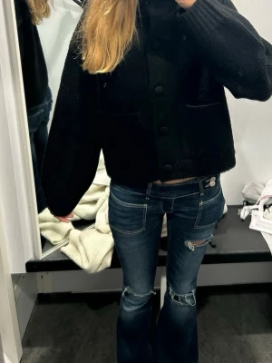 Mörkblå bootcut jeans med slitningar - Säljer ett par mörkblå bootcut jeans med slitningar vid knäna och lätt tvättade detaljer. Jeansen har låg midja och klassiska fem fickor. Perfekta för en avslappnad och trendig look.