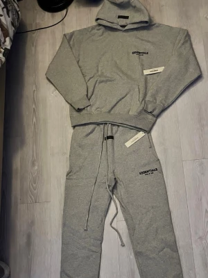Essentials Fear of God – Mörkgrå (M) / Komplett set - 🔥 Essentials Fear of God – Dark Grey (M) Snyggt mörkgrått Essentials-set som ger en fräsch och stilren look. Hoodien har logo på bröstet och byxorna matchar perfekt — superbekvämt material och riktigt skön passform. Perfekt för både vardag och streetwear. Fint skick! 🤍✨ 💬 Bud tas emot – pris går att diskutera! 📦 Skickas samma dag! 🧵 Material: bomullsblandning 🎨 Färg: mörkgrå / dark grey 📏 Storlek: M 👕 Set: hoodie + joggers 🌟 Passform: relaxed / essentials-fit  #Essentials #FearOfGod #GreySet #Da