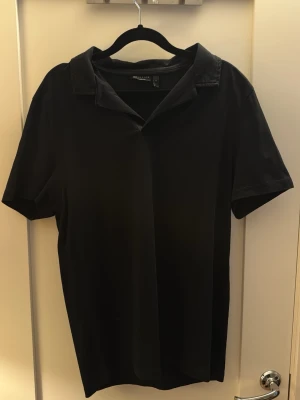 Svart piké från asos - Stilren svart piké från asos med korta ärmar och klassisk krage.