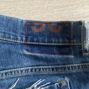 Blå skinny jeans från George - Snygga blå skinny jeans från George med klassisk femficksdesign och slitningar på benen för en cool look. Jeansen har skinny fit och är gjorda i mjukt denimtyg med orangea sömmar och detaljer vid bakfickan. (Det lilla metal D på bakfickan har försvunnit)